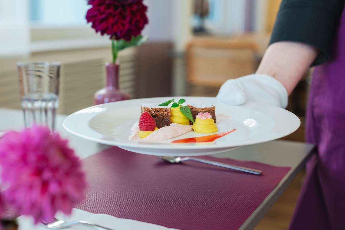 Lernende zur Ausbildung Hotelfachfrau serviert Dessert