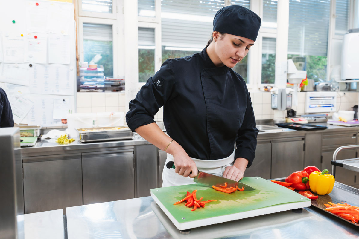 Lernende zur Ausbildung Köchin schneidet Paprika