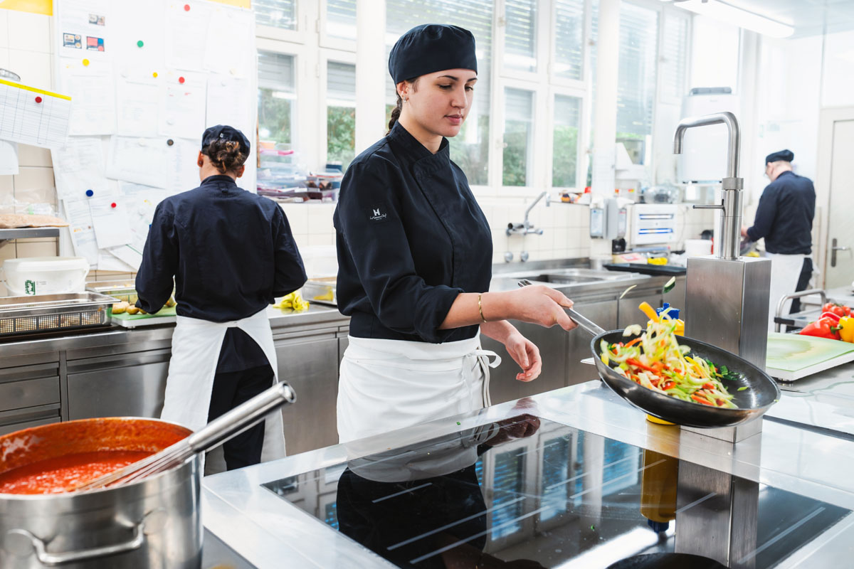Lernende zur Ausbildung Köchin mit Bratpfanne
